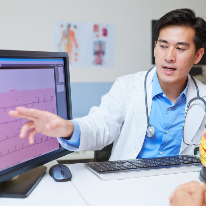 medical consultation - closeup side view asian elderly patient discussing cardiologist disease and electrocardiogram results with doctor using organ model in the clinic