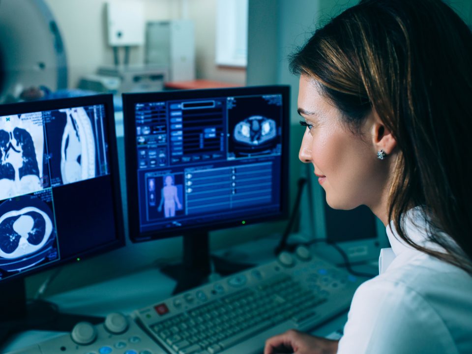 Radiologist reading a CT scan. Female doctor running CT scan from control room at hospital