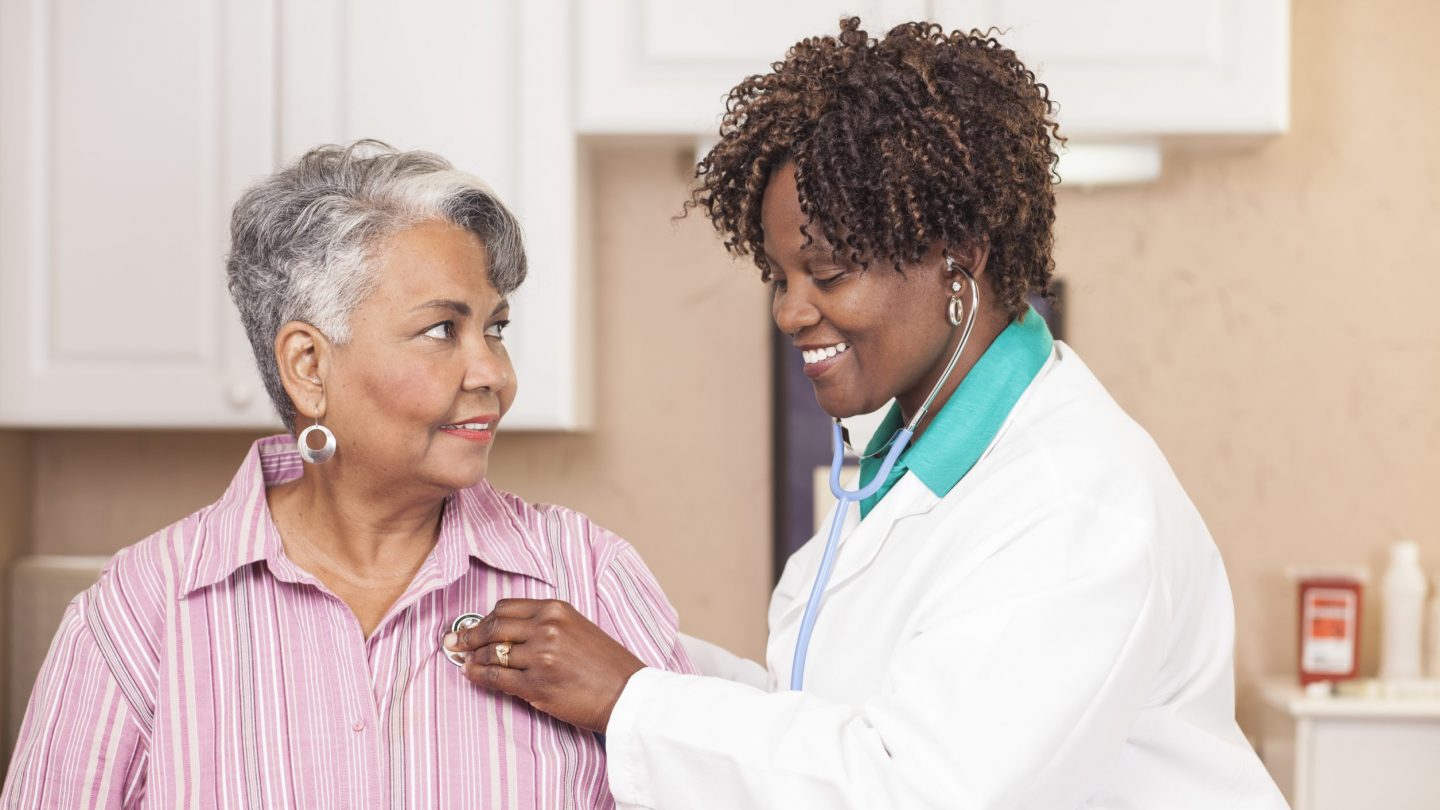 Doctor conducts medical exam on senior adult patient at clinic.