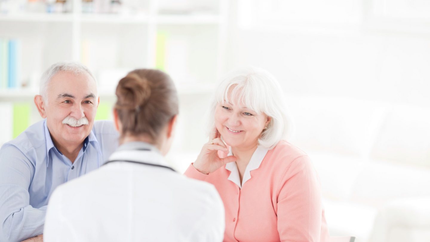 Senior woman with her husband at doctor's office measuring blood pressure.