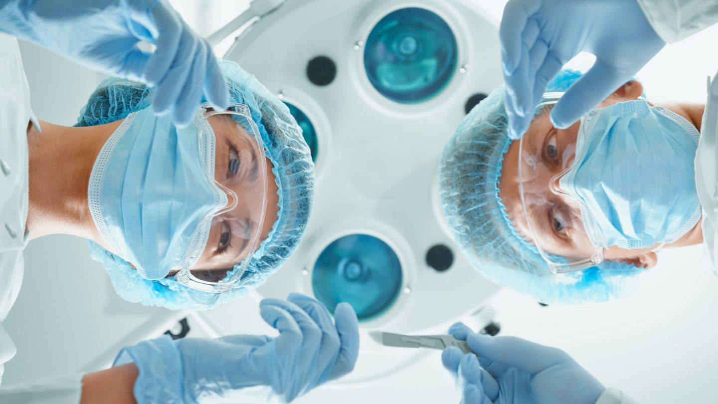 Nurse assistant passes a scalpel to surgeon
