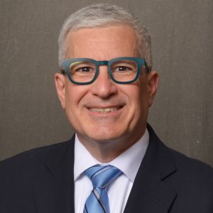 man wearing glasses in dark suit and tie