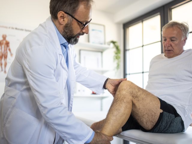 Doctor examining patient's leg injury at doctor's office